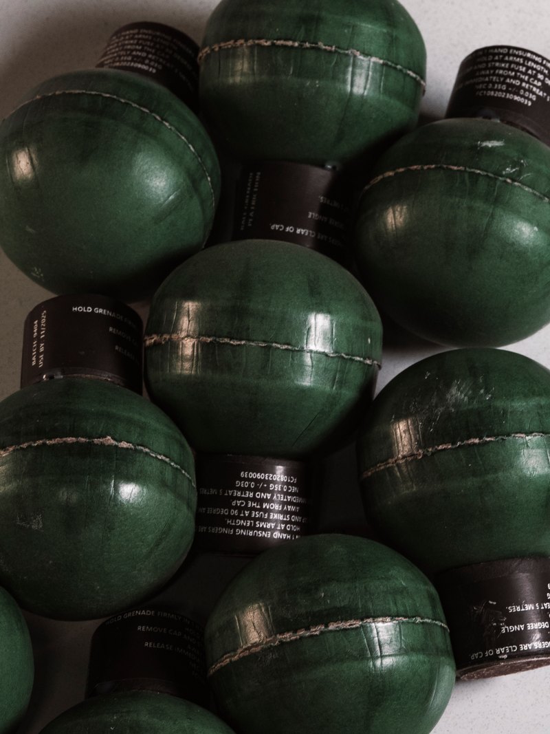 A pile of green ball grenades with dark fuse caps