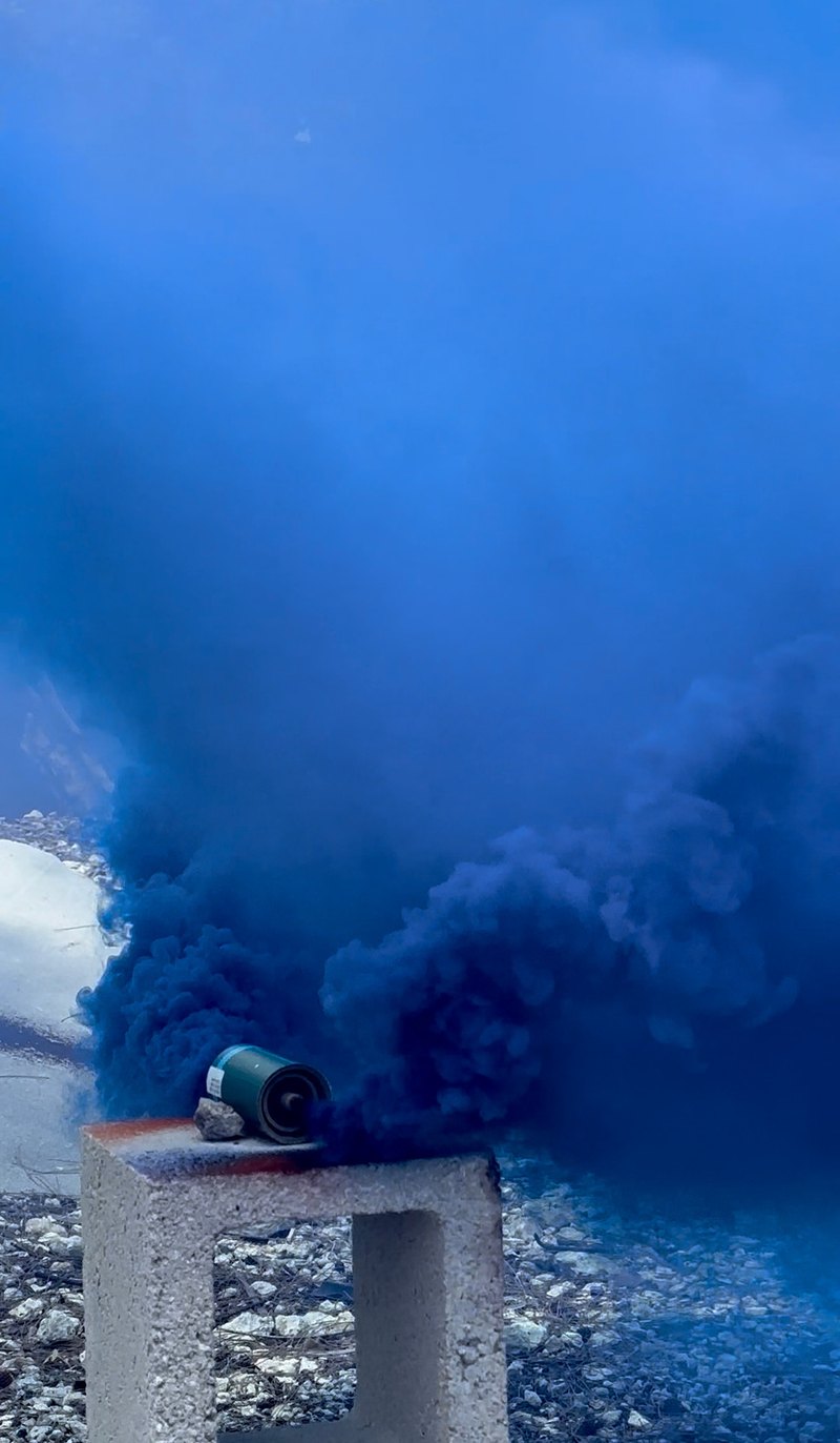 Blue smoke billowing from a canister set on a concrete block