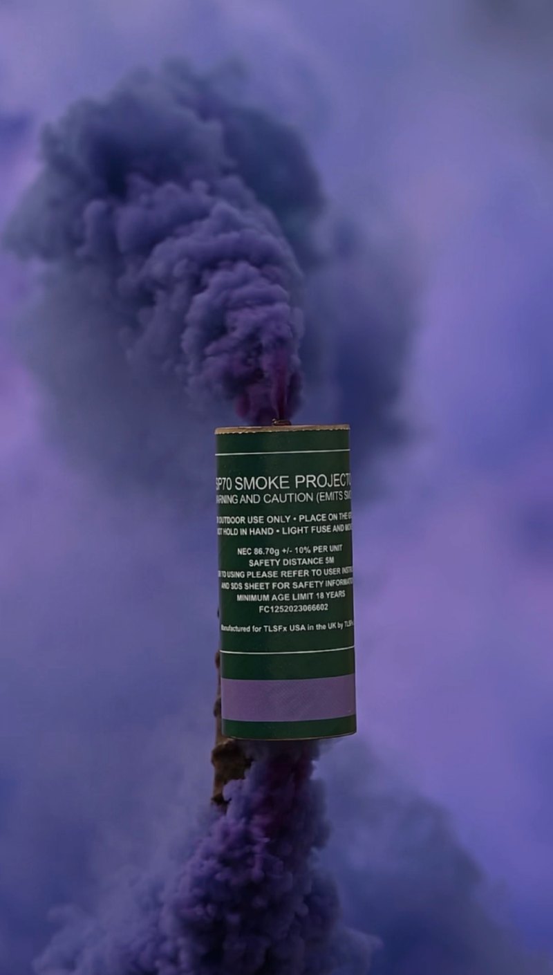 Purple smoke rising from an SP70 smoke grenade canister held up on a stake