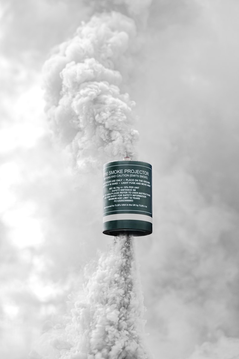 White smoke rising from a smoke grenade canister held up on a stake